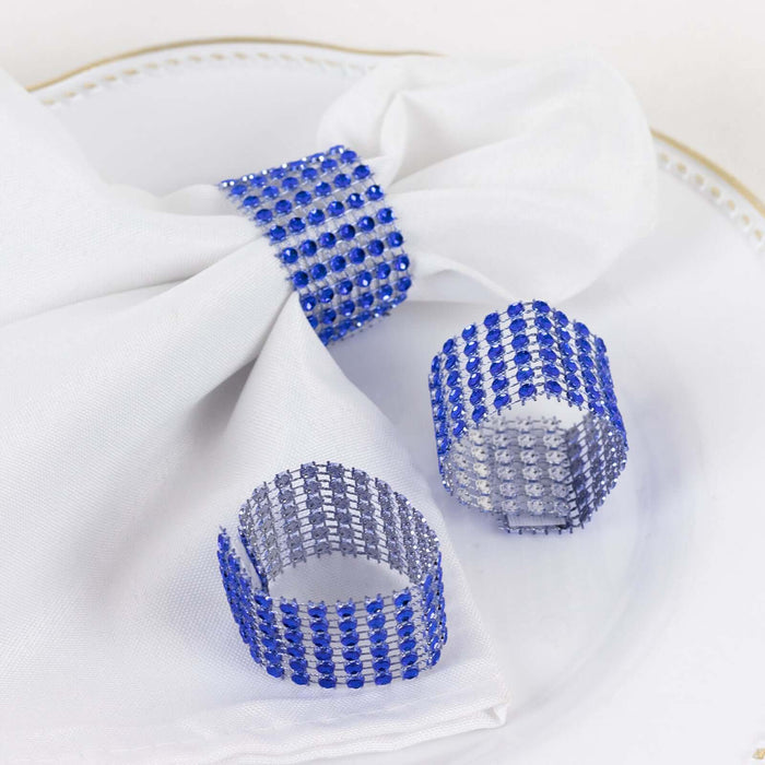 Blue rhinestone napkin rings and napkin on a plate.