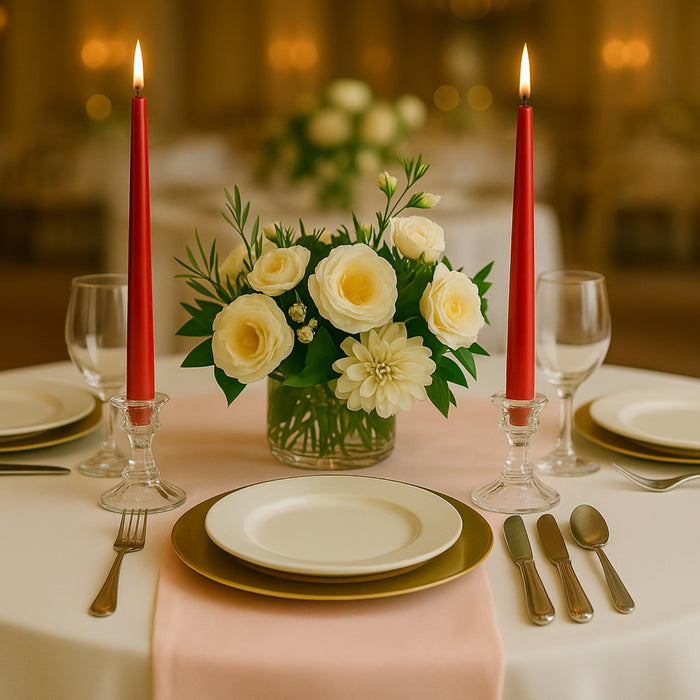 Elegant table setting with white roses, red candles, and fine dining utensils.