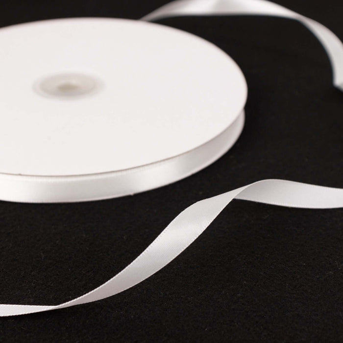 White satin ribbon on a black surface, elegantly curved.