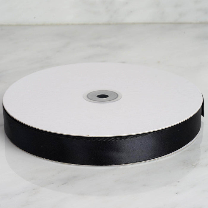 Black satin ribbon on a spool, perfect for crafting and gift wrapping. #whtbkgd