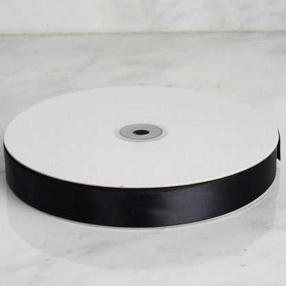 Black satin ribbon on a spool, perfect for crafting and gift wrapping. #whtbkgd