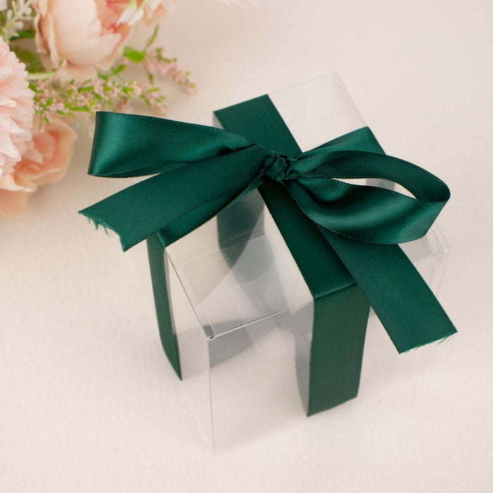 Clear gift box with green ribbon, surrounded by soft pink flowers.