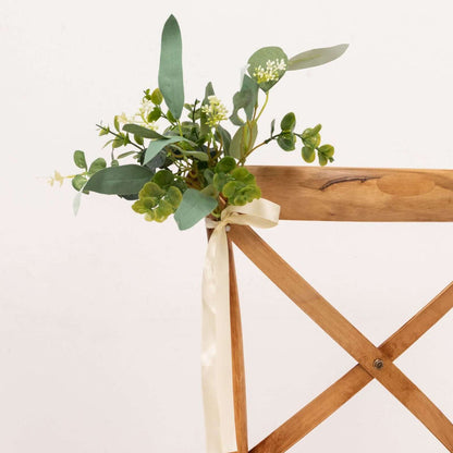 Floral arrangement tied to a wooden chair with a ribbon.