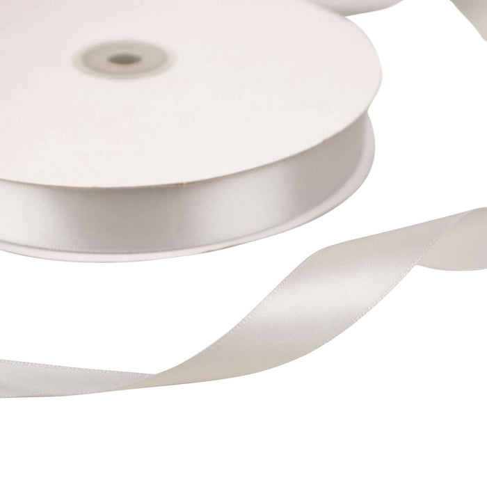 White satin ribbon on a spool with a loose end.