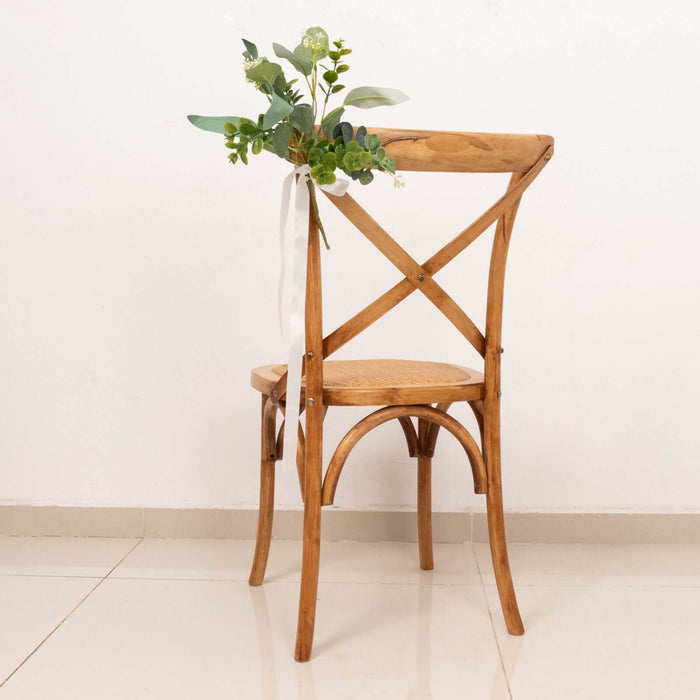 Wooden cross-back chair with greenery decoration.