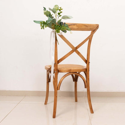 Wooden cross-back chair with greenery decoration.