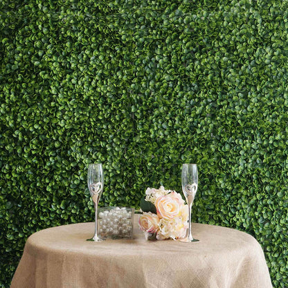 Elegant table setting with glasses and flowers against a green foliage backdrop.