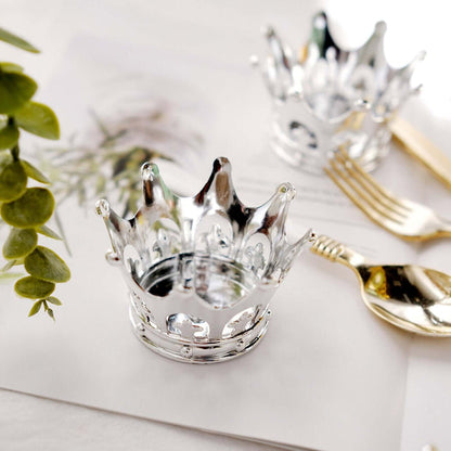 Silver crown-shaped candle holder on a table with decorative elements.
