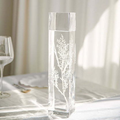 Elegant glass vase with intricate botanical design, filled with water.
