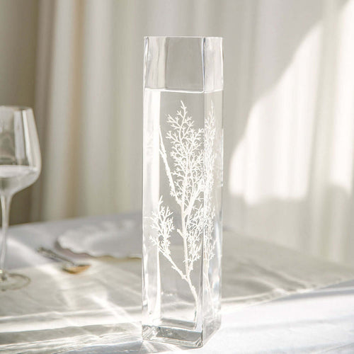 Elegant glass vase with intricate botanical design, filled with water.