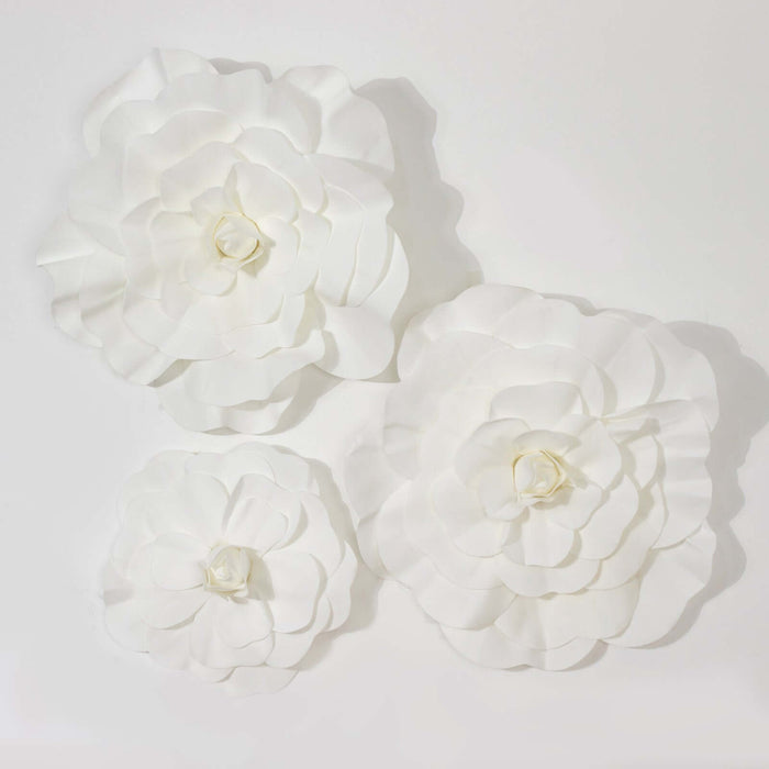 White paper flowers in three sizes, beautifully arranged on a plain background.