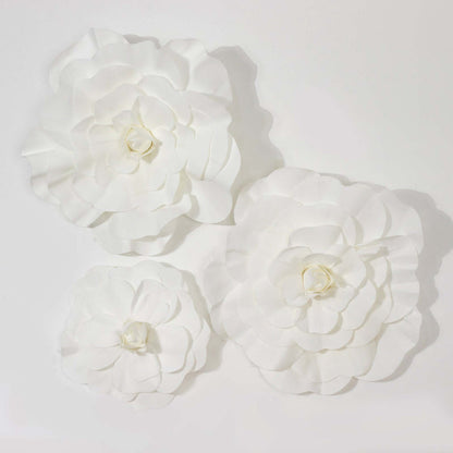 White paper flowers in three sizes, beautifully arranged on a plain background.