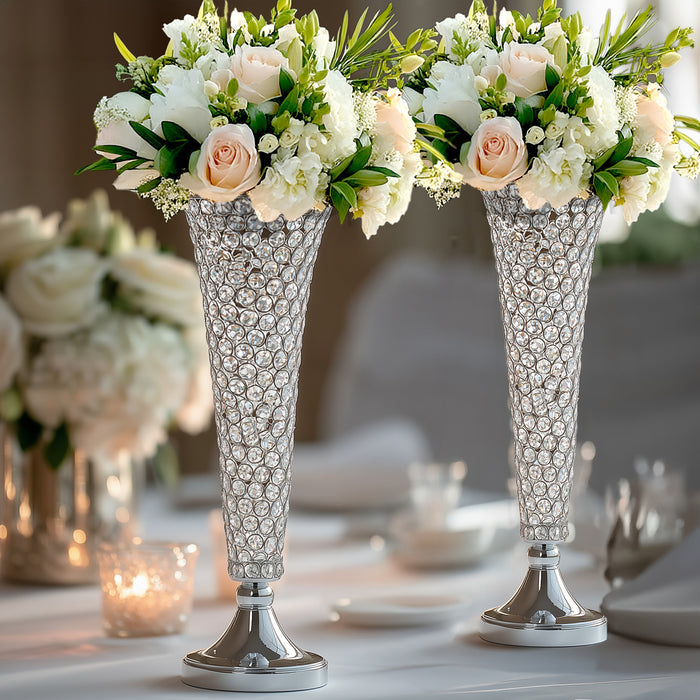 Elegant crystal flower vases with roses and white blooms on a dining table.