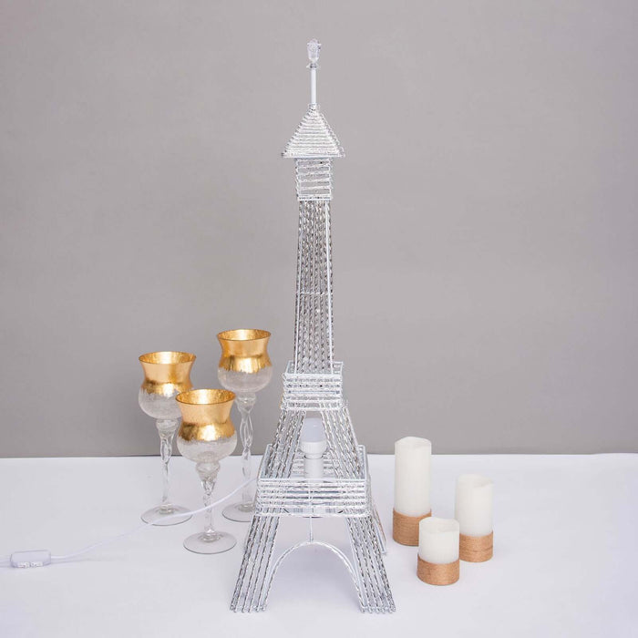 Silver Eiffel Tower lamp with decorative glasses and candles.