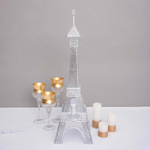 Silver Eiffel Tower lamp with decorative glasses and candles.