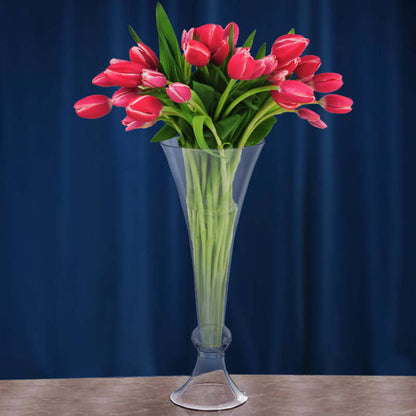 Clear vase with pink tulips against a blue backdrop.