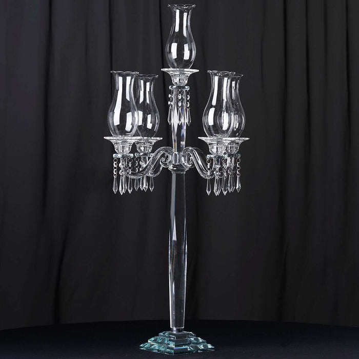 Elegant crystal candelabra with three glass shades on a dark background.