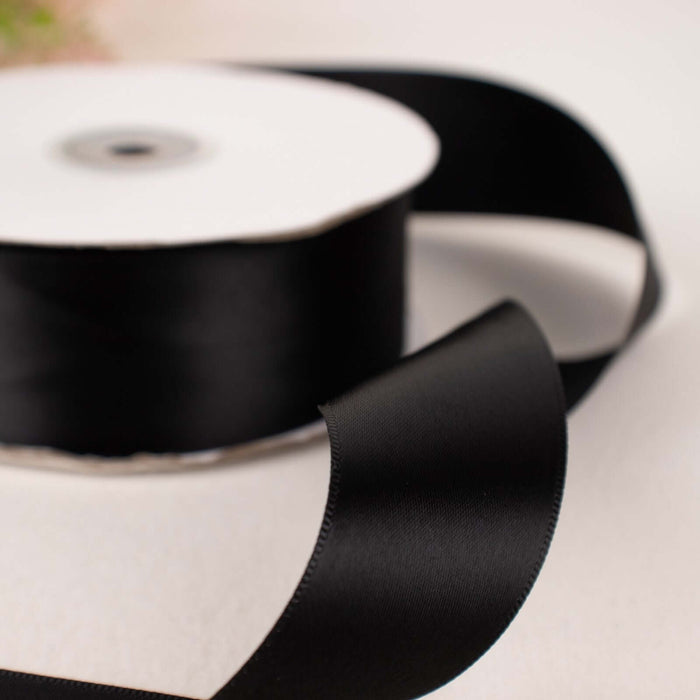 Black satin ribbon on a spool, elegantly draped.