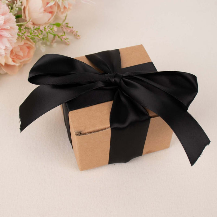 Gift box wrapped in black ribbon on a neutral background.