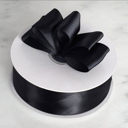 Black satin ribbon on a spool with a bow