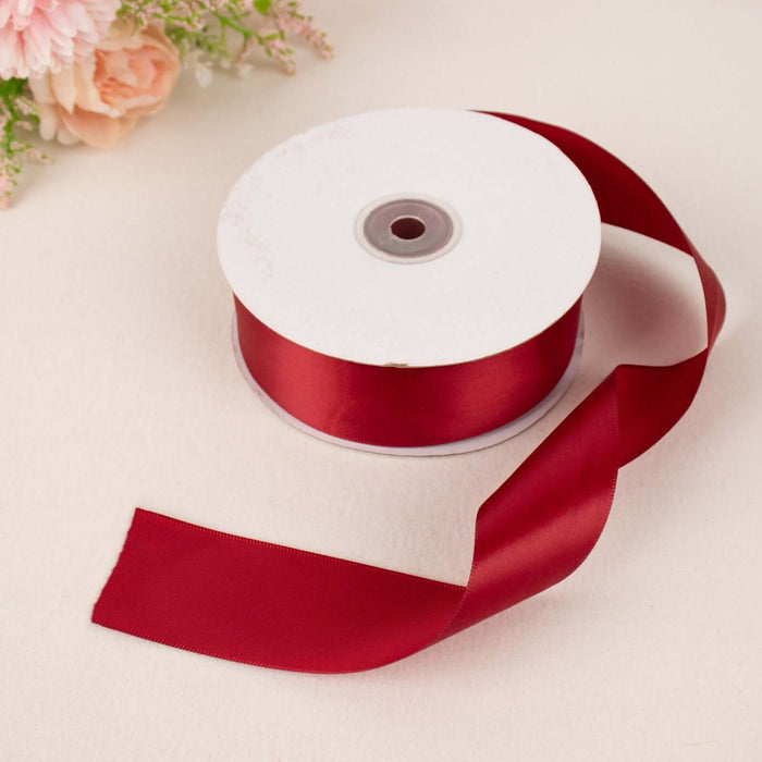 Red satin ribbon on a spool with a trailing end.