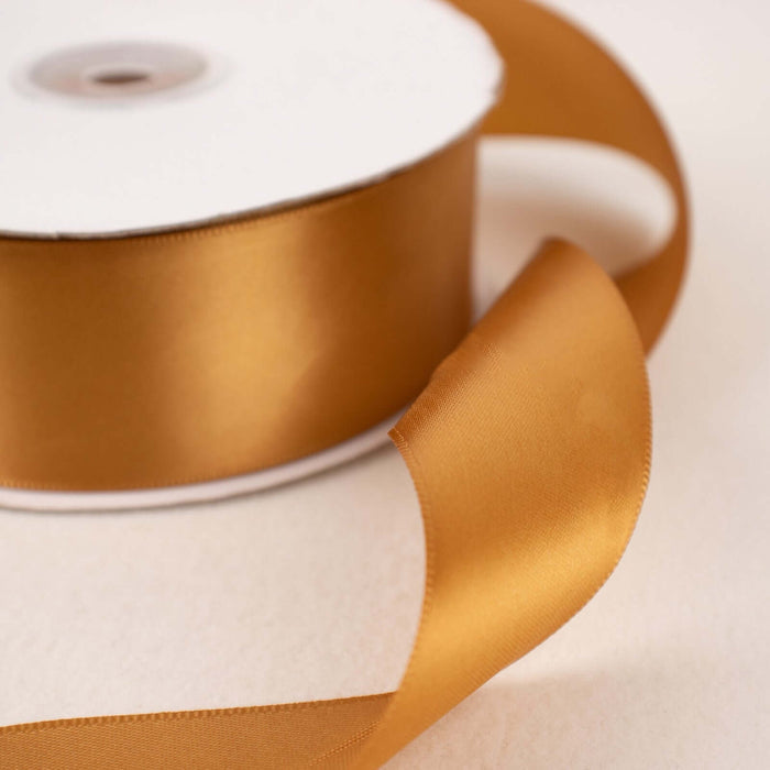 Gold satin ribbon roll on a neutral background.