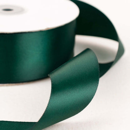 Green satin ribbon on a spool with a flowing end.