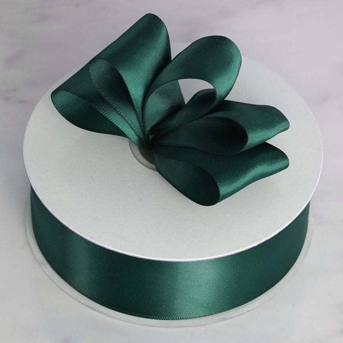Green satin ribbon with bow on spool, perfect for gift wrapping.