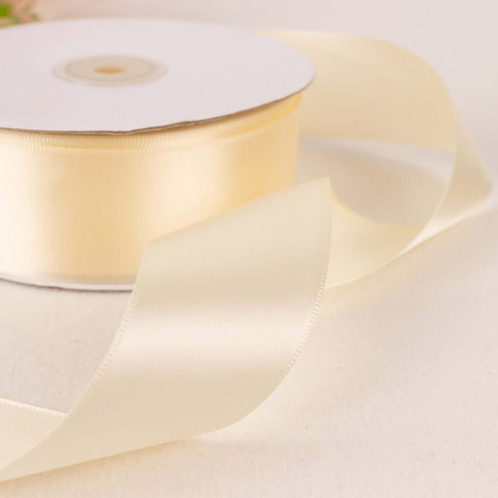 Cream satin ribbon roll with a flowing ribbon on a light background.