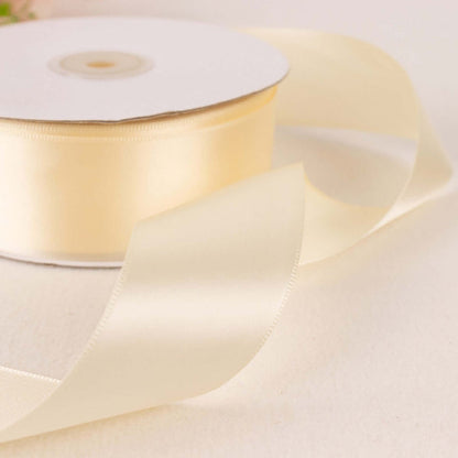 Cream satin ribbon roll with a flowing ribbon on a light background.