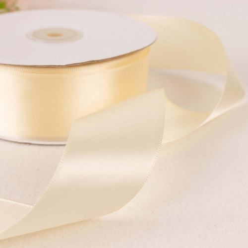Cream satin ribbon roll with a flowing ribbon on a light background.