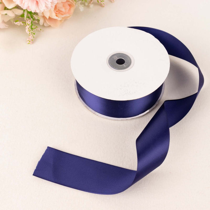 Navy blue satin ribbon on a spool with a loose end