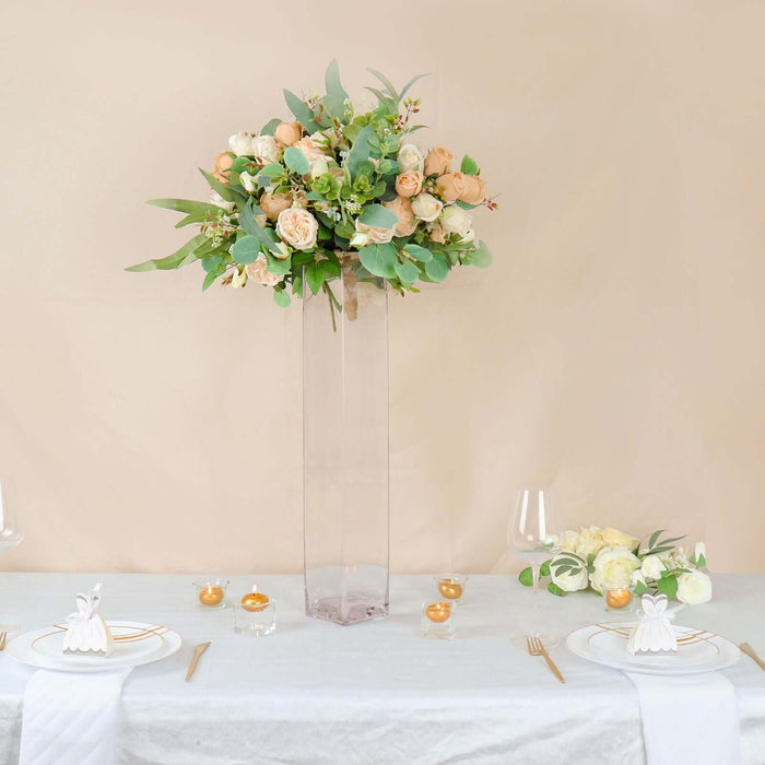 Elegant floral arrangement in a tall vase for a sophisticated table setting.