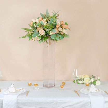 Elegant floral arrangement in a tall vase for a sophisticated table setting.