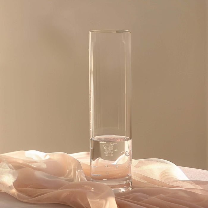 Clear glass vase with water and soft fabric backdrop.