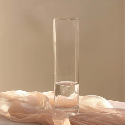 Clear glass vase with water and soft fabric backdrop.