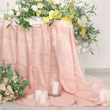 Elegant pink tablecloth with floral arrangement and candles in a stylish setting.