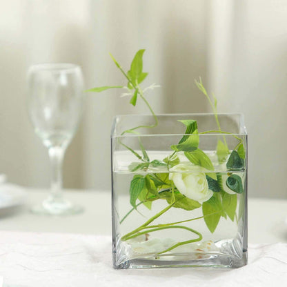 Glass vase with greenery and flowers in water, elegantly styled.