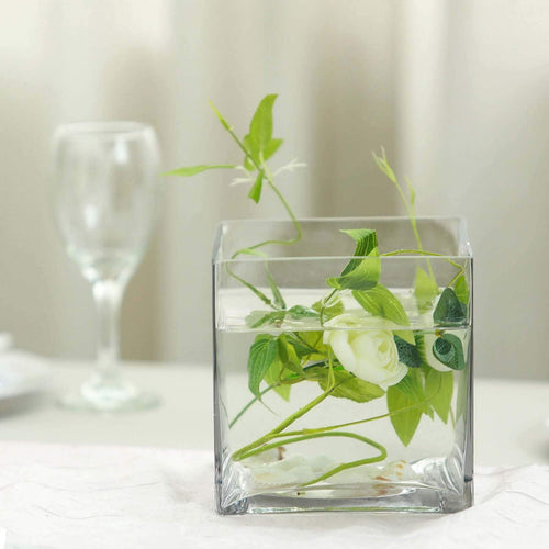 Glass vase with greenery and flowers in water, elegantly styled.