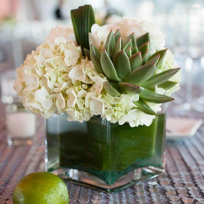 Elegant floral arrangement with hydrangeas and succulents in a glass vase.