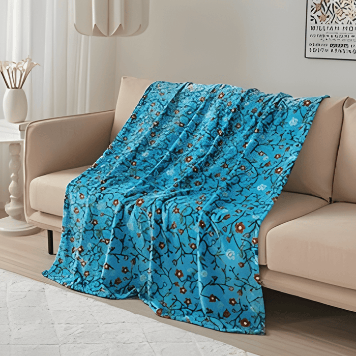 Anishinaabe Enchantment Throw Blanket draped on a couch, showcasing vibrant traditional designs on soft fabric.