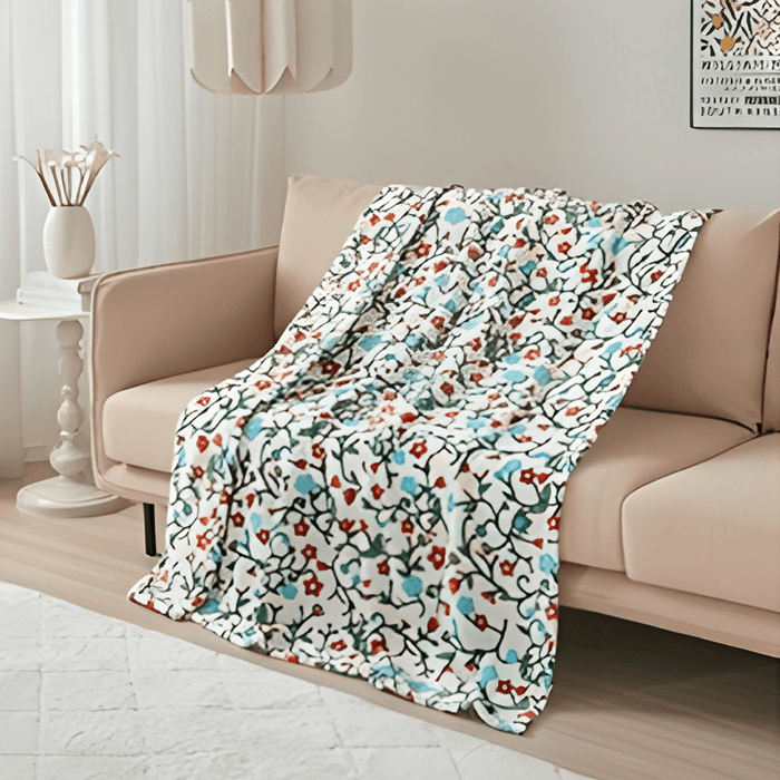 Anishinaabe Enchantment Throw Blanket draped on a couch, featuring vibrant traditional designs and soft material.