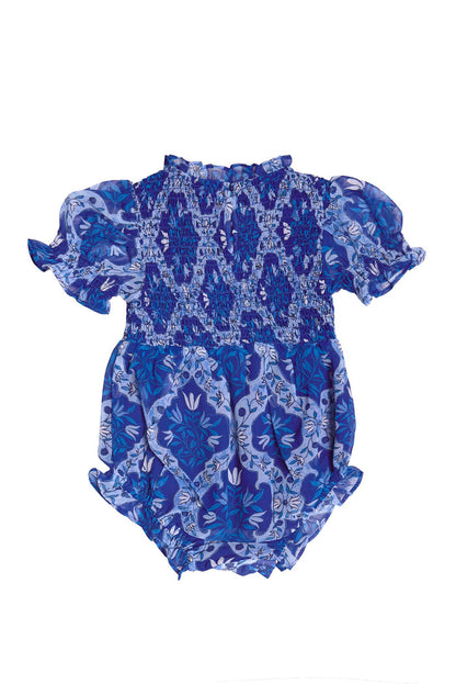 The Ivy City Co Baby Cordelia Romper in Trellis Foulard features a smocked bodice, puffed short sleeves, and ruffled leg openings in a blue and purple floral print—an adorable choice for an Easter outfit.