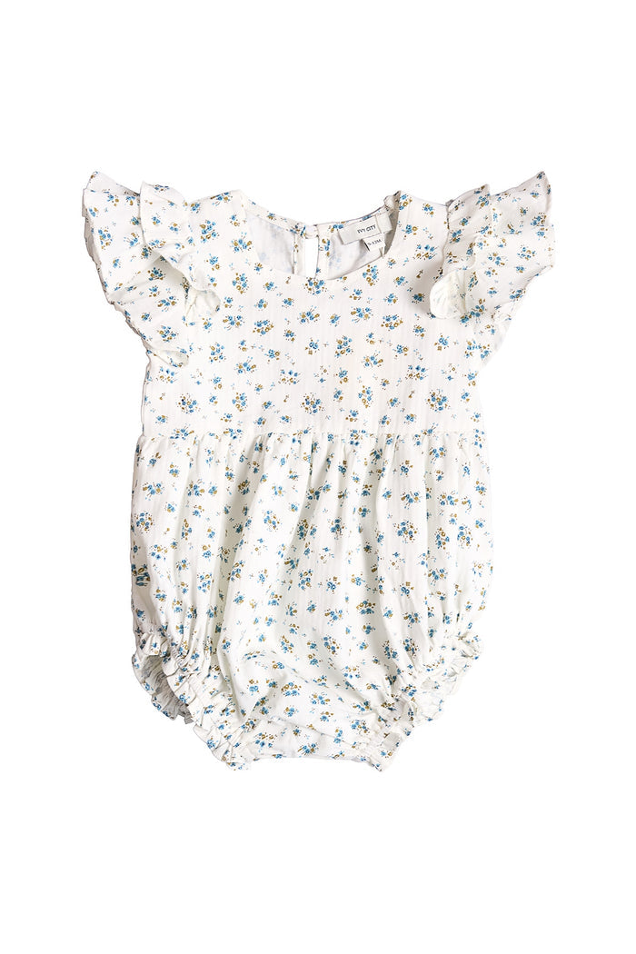 The Ivy City Co Baby Hattie Romper in Madeline Blue features soft white cotton, short ruffled sleeves, a delicate blue floral print, gathered waist and legs, and an easy back button closure—perfect for special occasions.