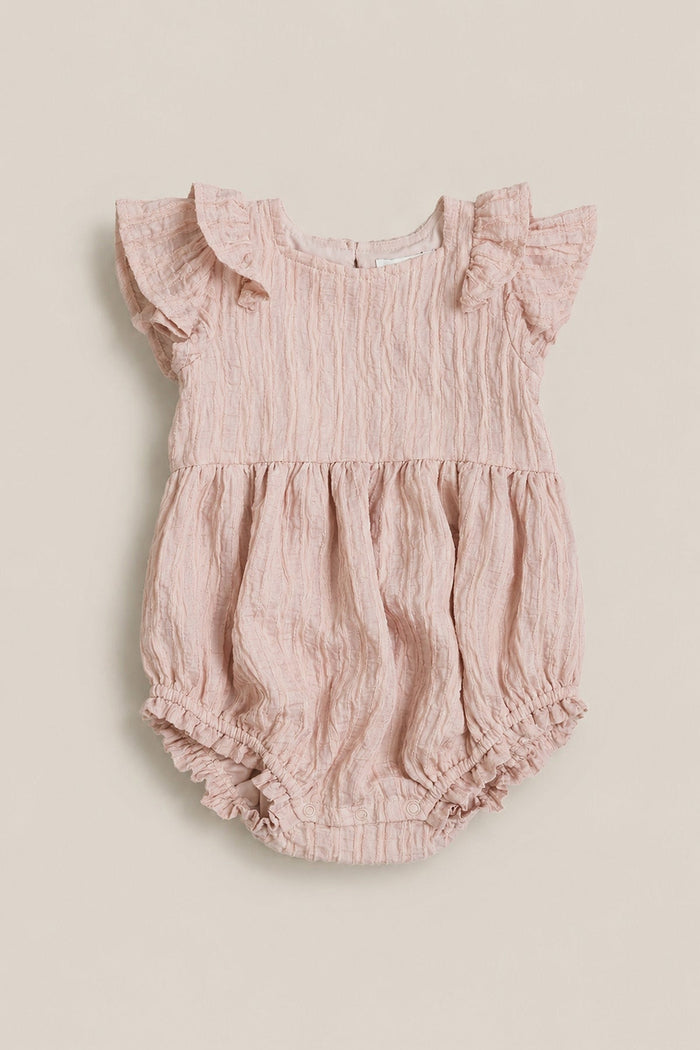 The Baby Hattie Romper in Pink Stripes by Ivy City Co features short ruffled sleeves, a gathered waist, and charming ruffled leg openings. The crinkled fabric adds a sweet touch, while a small button closure at the back makes dressing easy. Pair with Mom and Me matching outfits from Ivy City Co for an adorable coordinated look.