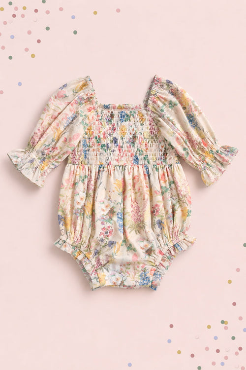 The Ivy City Co Baby Madeline Romper in Cordelia Floral features long puffed sleeves, ruffled cuffs, and a smocked bodice on pale pink with pastel confetti dots—perfect for adorable mommy-and-me moments.