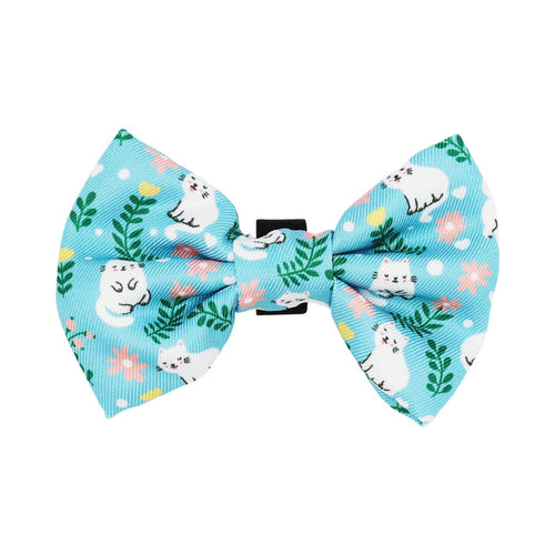 The Sassy Woof Cat Bowtie - Purrs & Petals features a blue fabric with white cat illustrations, pink flowers, green leaves, and polka dots. Pair it with a matching leash or adjustable harness for a stylish feline ensemble.