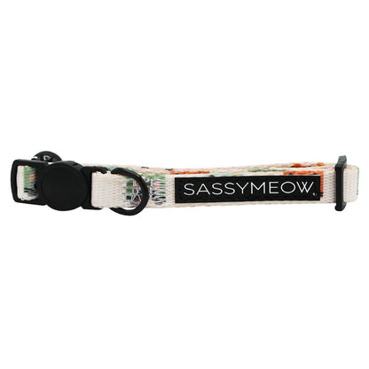 The Sassy Woof Cat Collar - Smitten Kittens is a white, adjustable neoprene kitten collar with a black buckle and tag reading "SASSYMEOW" in white. It features a subtle multicolor pattern and an adjustable strap for comfort.
