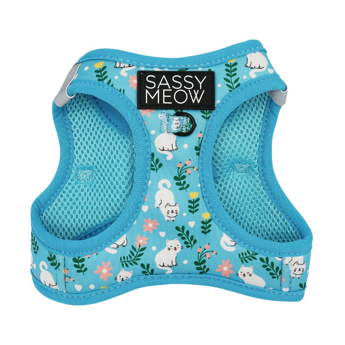 The Sassy Woof Cat Step-In Harness - Purrs & Petals features blue floral fabric with cute white cats, green leaves, pink flowers, a black SASSY MEOW label, comfy custom neoprene mesh lining, and an AirTag pocket for added security.