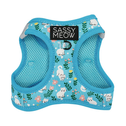 The Sassy Woof Cat Step-In Harness - Purrs & Petals features blue floral fabric with cute white cats, green leaves, pink flowers, a black SASSY MEOW label, comfy custom neoprene mesh lining, and an AirTag pocket for added security.